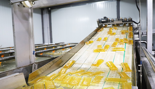 Yellow hot melt adhesive pillow packs moving on a conveyor on a production line, image published by the manufacturer