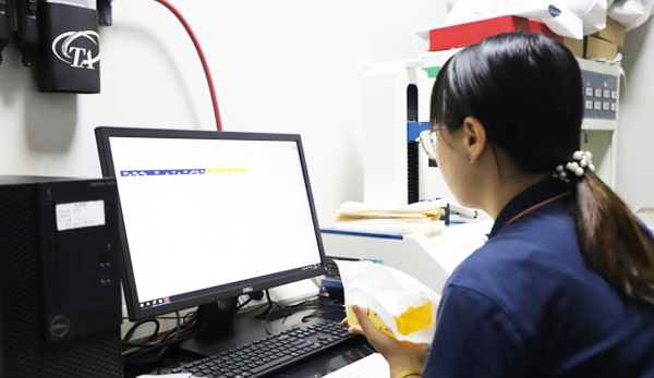 Technician holding a yellow adhesive sample at a laboratory workstation, image published by the manufacturer
