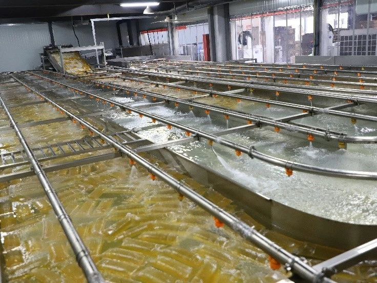 Yellow hot melt adhesive blocks cooling in a water bath on a production line, image published by the manufacturer